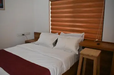a bed with white pillows and a wooden headboard at Forest Brew Resort Wayanad in Chekadi
