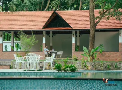 a man sitting at a table in front of a house at Athirapilly Ontherocks in Athirappilly