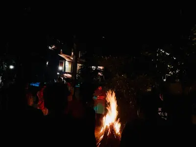 a group of people sitting around a fire at night at Athirapilly Ontherocks in Athirappilly