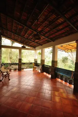a large porch with benches on a tiled floor at WellGrown- The Farmhouse at Kombai - Pallangi, Kodaikanal in Kodaikānāl