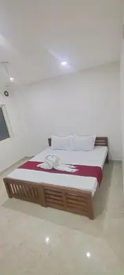 a bed in a white room with avertisement at VKJ Lodge in Alwaye