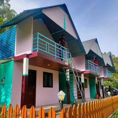 a house with a balcony and a man standing on the balcony at haven bridge Homestay in Meenangadi