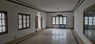 an empty room with white walls and windows at Shariff Villa in Mysore