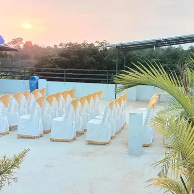 a row of white chairs sitting on a patio at Tour Way Nadavayal Inn in Kenichira