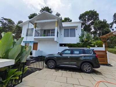 a green suv parked in front of a white house at Aloravillasbooking in Wayanad