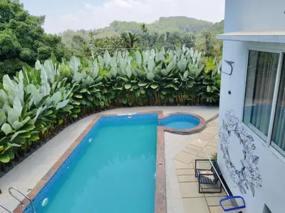 a swimming pool on a house with a garden at Aloravillasbooking in Wayanad