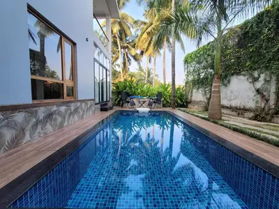 a swimming pool in a villa with palm trees at Aurora The Pool Villa in Kozhikode