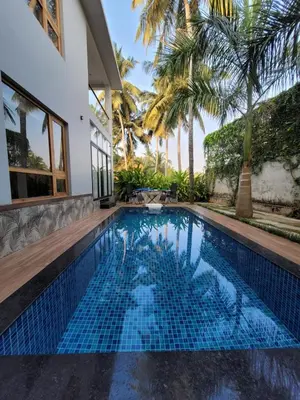 a swimming pool in the backyard of a house with palm trees at Aurora The Pool Villa in Kozhikode