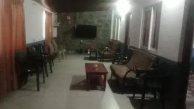 a living room with chairs and a table and a tv at Varshinicottage kothkiri in Kotagiri