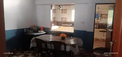 a dining room with a table and a kitchen at Varshinicottage kothkiri in Kotagiri