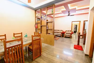 a dining room and living room with a table and chairs at San WAYANAD HOMESTAY AND SERVICE VILLA in Sultan Bathery