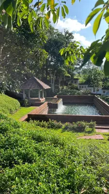 a large pond in a park with a gazebo at Hortus Malabaricus Garden Resort in Cheruthuruthi
