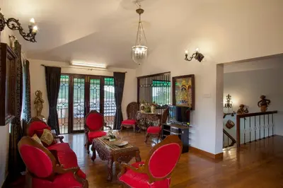a living room with red chairs and a tv at Away From Home - 2 - Home Stay Ooty, Entire 4BHK Villa in Ooty