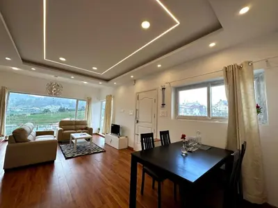 a living room with a dining room table and a living room with a couch at Away From Home - 3 - HomeStay Ooty, Entire 3BHK Villa in Ooty