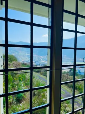 a view through a window looking out at the countryside at Away From Home - 1 - Rooms In Ooty, Home Stay Ooty in Ooty