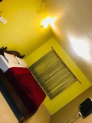 a bedroom with a bed with a red comforter and a window at Greenyard cottage in Ooty