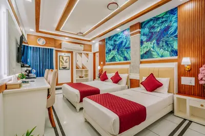 a hotel room with two beds and a desk at Excellency Airport Hotel in Ernakulam