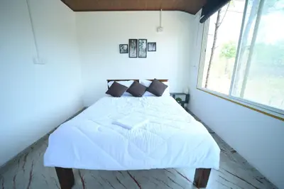 a white bed in a room with a window at Kashi's stay in Kushālnagar
