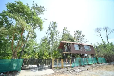 a house with a fence in front of trees at Kashi's stay in Kushālnagar