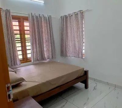a bedroom with a bed and two windows at Karukutty Rental House in Adūr