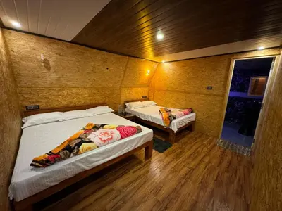 two beds in a small room with wooden floors at Fairyland Resort in Kodaikānāl