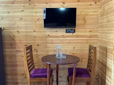 a table with two chairs and a television on a wall at Fairyland Resort in Kodaikānāl