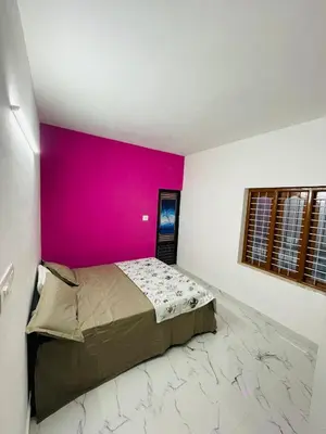 a bedroom with a pink wall and a bed at In-woods stay in Olavakod Junction