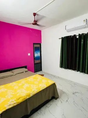 a bedroom with a yellow bed and a pink wall at In-woods stay in Olavakod Junction
