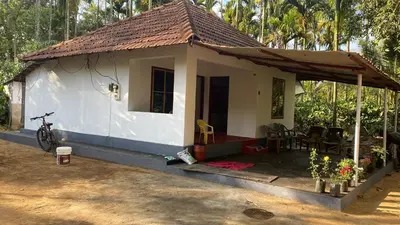 a small white house with a table and chairs at Carta Blanca in Mananthavady