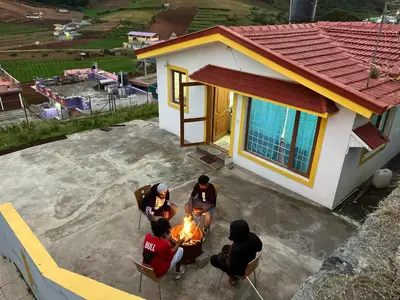 a group of people sitting around a fire in front of a house at Chillz Heaven Resorts - Ketti Palada in Coonoor