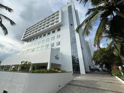 a building with palm trees in front of it at Gokulam Grand Kozhikode in Kozhikode
