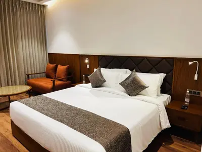 a hotel room with a large bed and a chair at Gokulam Grand Kozhikode in Kozhikode