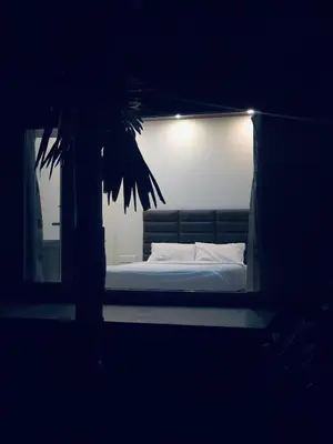 a bed in a dark room with a palm tree at Mountain river farm resort in Agali