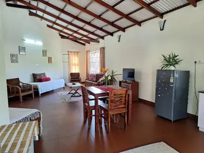 a living room with a table and a refrigerator at Pristine Stay by LexStays in Coonoor