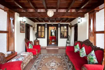a living room with red couches and a rug at The Blue Mountains Estate Stay in Madikeri