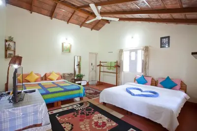 a bedroom with two beds and a television in it at The Blue Mountains Estate Stay in Madikeri