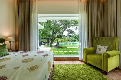 a bedroom with a bed and a chair and a large window at Le Jardin - Luxury Private Pool Villa near Kochi, Kerala in Ernakulam