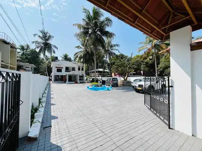 a driveway of a house with a fence and palm trees at Aagneyam mansion in Kozhikode