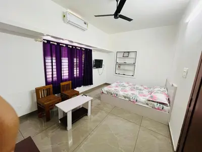 a bedroom with a bed and a table and a chair at Aagneyam mansion in Kozhikode