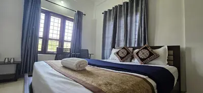 a bedroom with a large bed with blue curtains at Brighton Stays in Sultan Bathery