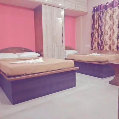 two beds in a room with pink walls at Sri Sapthagiri comfort in Mysore