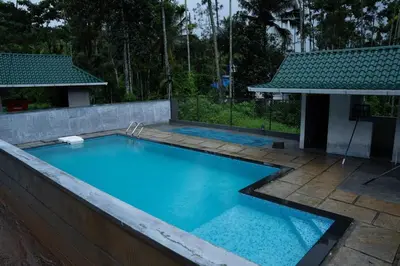 a swimming pool with blue water in a backyard at LilliputHaven Treehut in Sultan Bathery