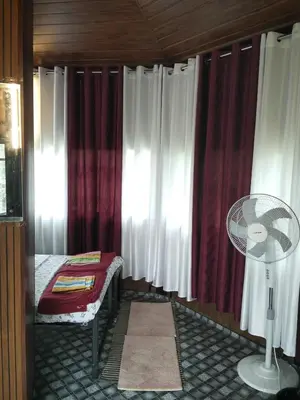 a bedroom with red and white curtains and a fan at LilliputHaven Treehut in Sultan Bathery