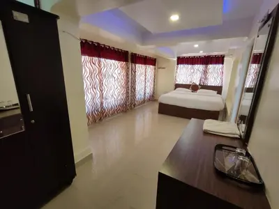a bedroom with a bed and a window with red curtains at R R K Residency in Ooty