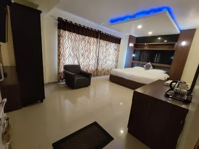 a bedroom with a bed and a chair and a desk at R R K Residency in Ooty