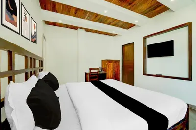a bedroom with a white bed and a flat screen tv at Super Collection O Charing Cross Ooty in Ooty