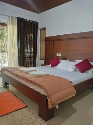 a bedroom with a large bed with red pillows at Bharathapuzha resort in Kārakkād
