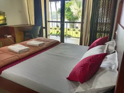 a bedroom with a bed with red and white pillows at Bharathapuzha resort in Kārakkād