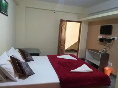 a bedroom with a bed with a red blanket on it at Sri Sai Residency Ooty in Ooty
