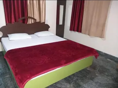 a bedroom with a bed with a red blanket on it at Sri Sai Residency Ooty in Ooty